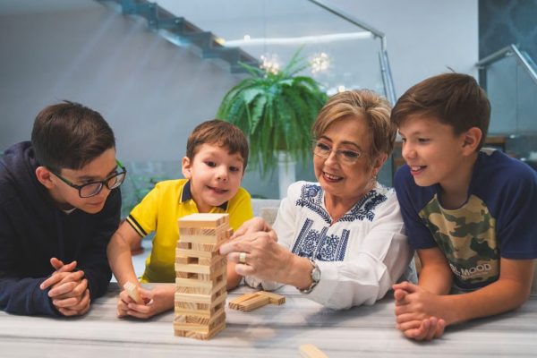 A joyful family moment with grandma and grandsons playing Jenga indoors, capturing quality time together.