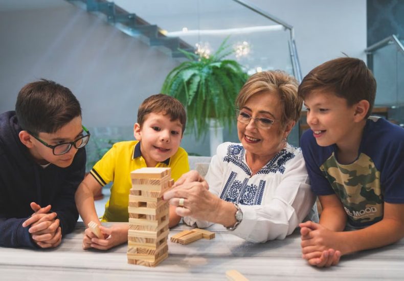 A joyful family moment with grandma and grandsons playing Jenga indoors, capturing quality time together.